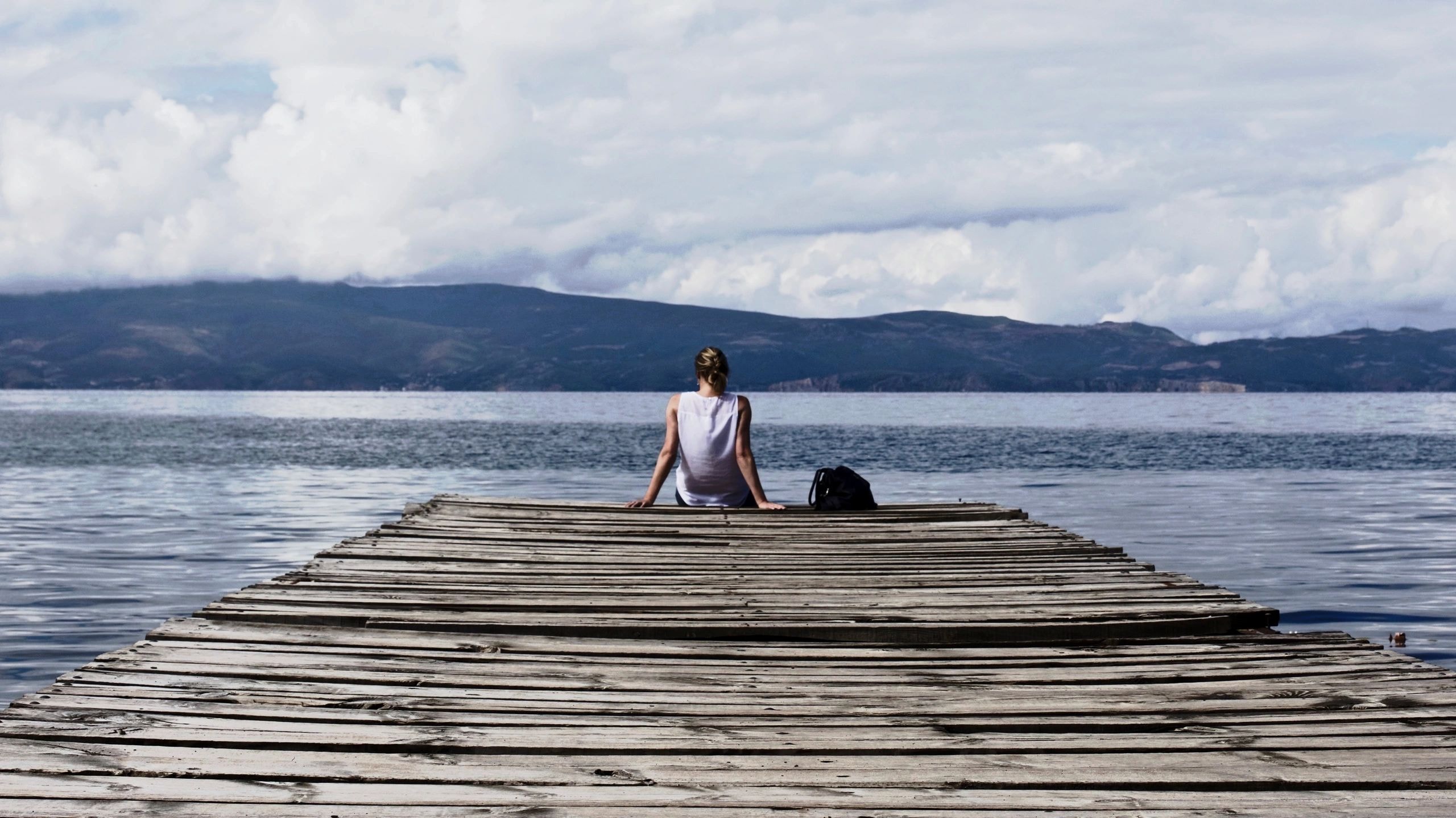 Person sitting peacefully by a lake at dusk